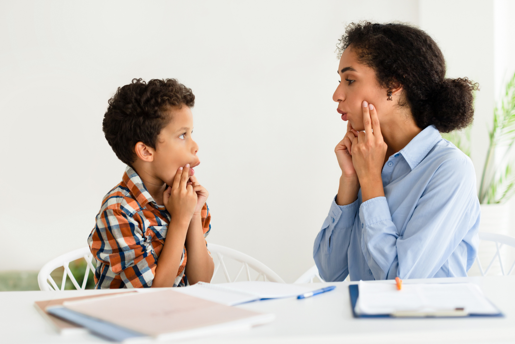 A woman teaching a child how to pronounce a word