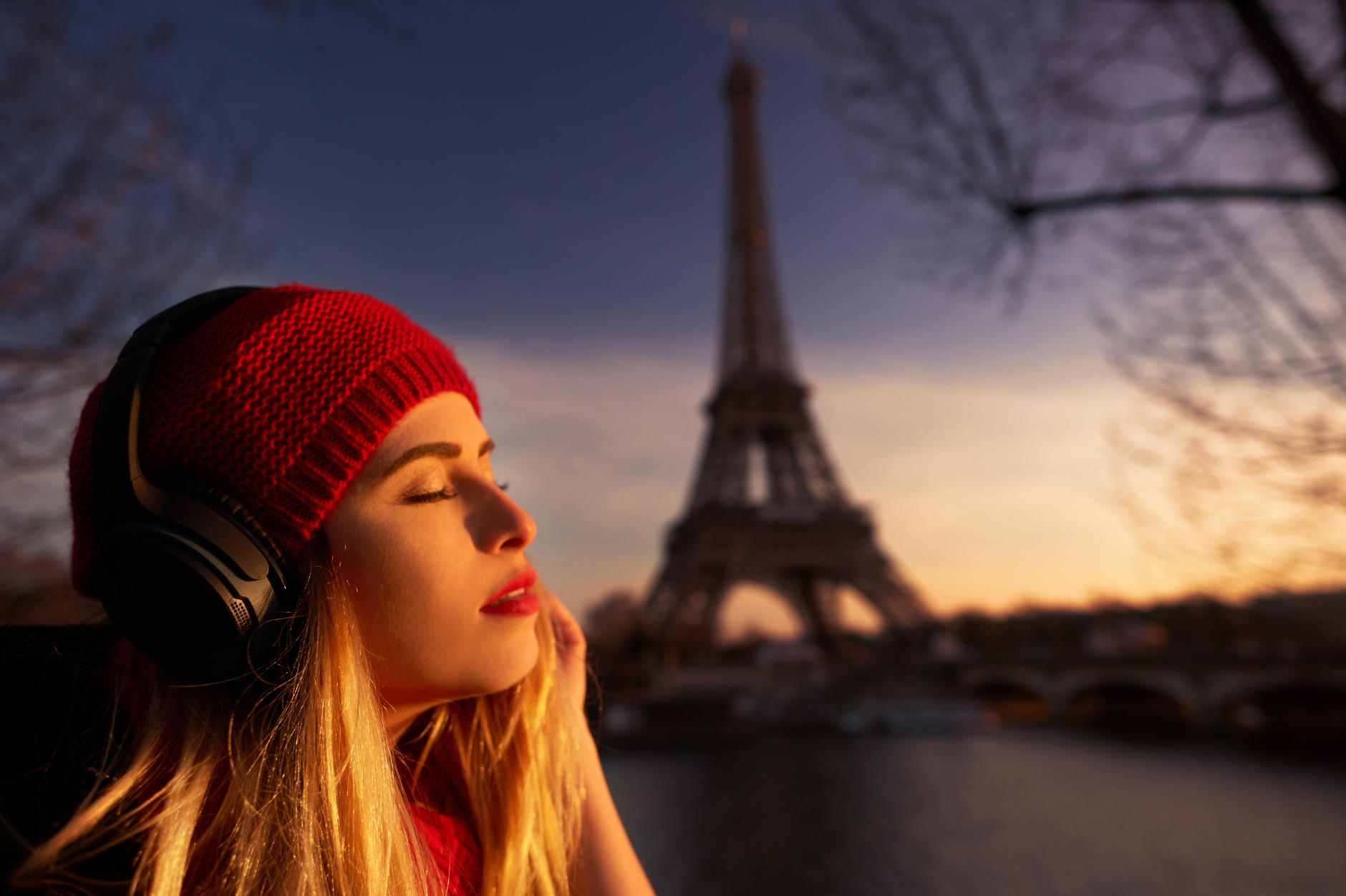 Girl in front of the Eiffel Tower listening to music with headphones