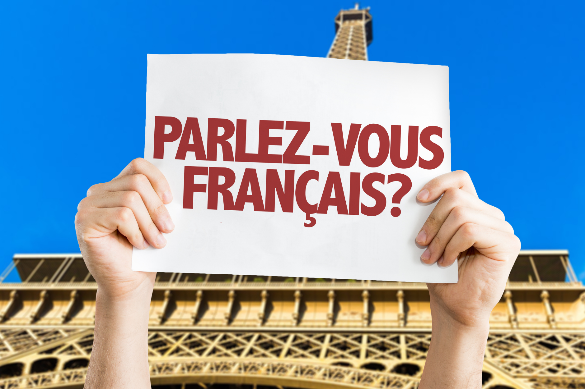 A placard in front of the Eiffel Tower reading 'Parlez-vous français ?'