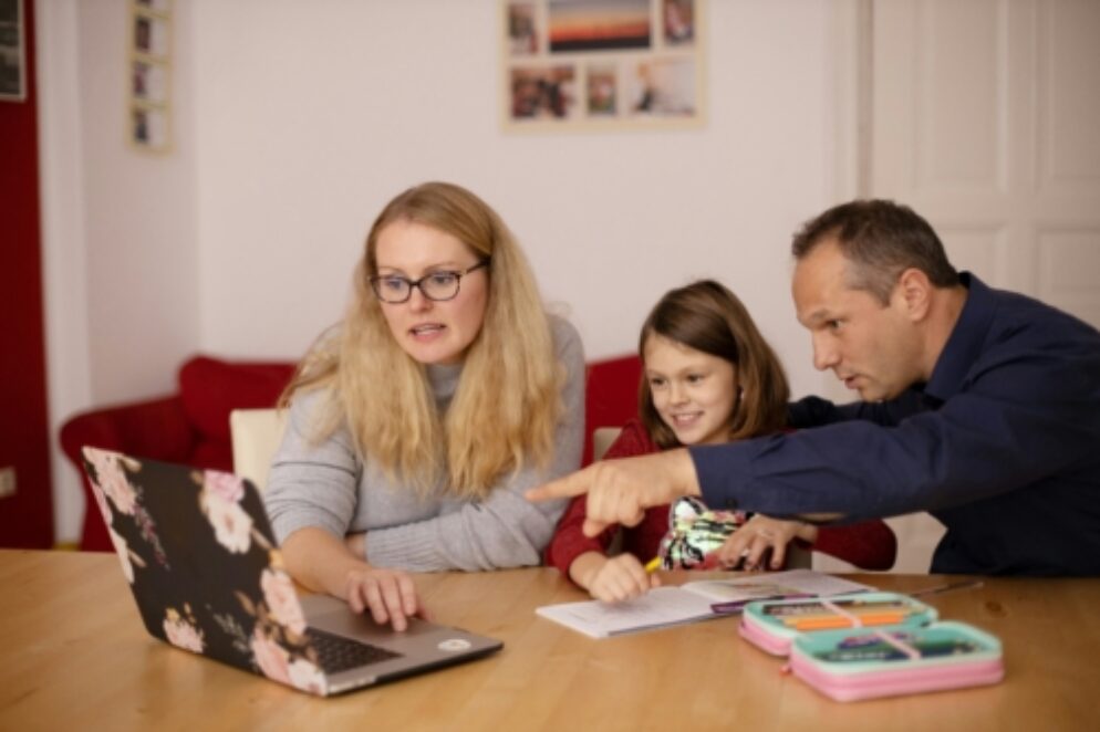 Two parents teaching their daughter from a laptop