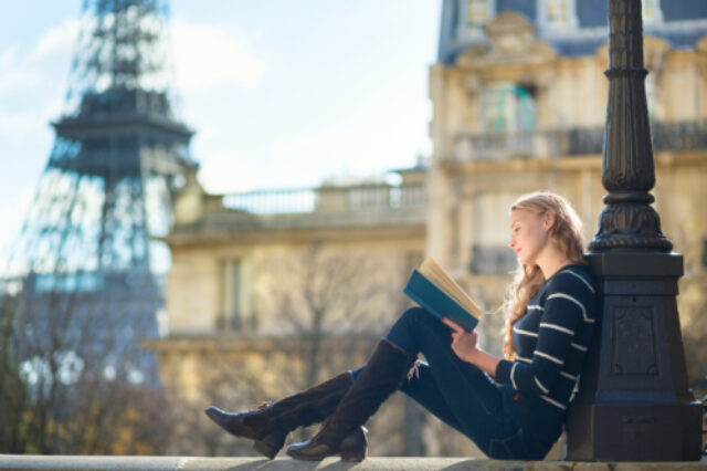 Woman reading a book near the Eiffel Tower