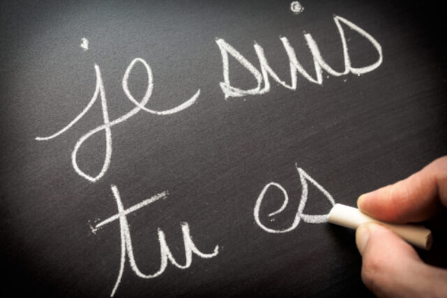 Hand writing verbs on a chalkboard