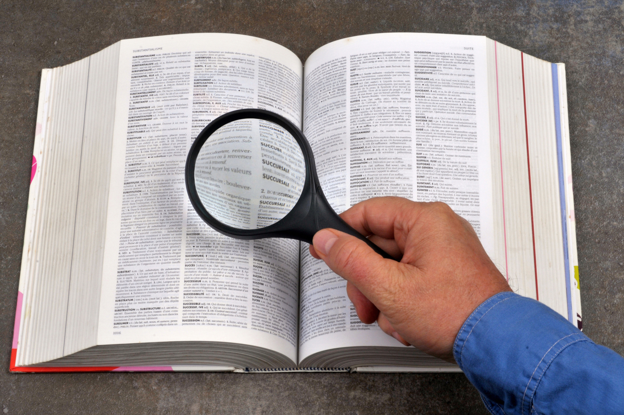 Someone using a magnifying glass to read a dictionary