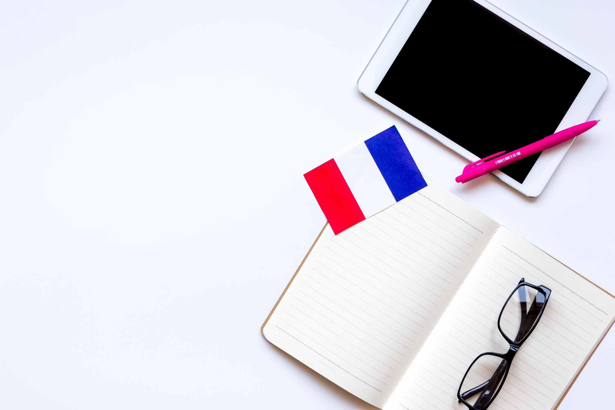 An open book and tablet with a pair of glasses