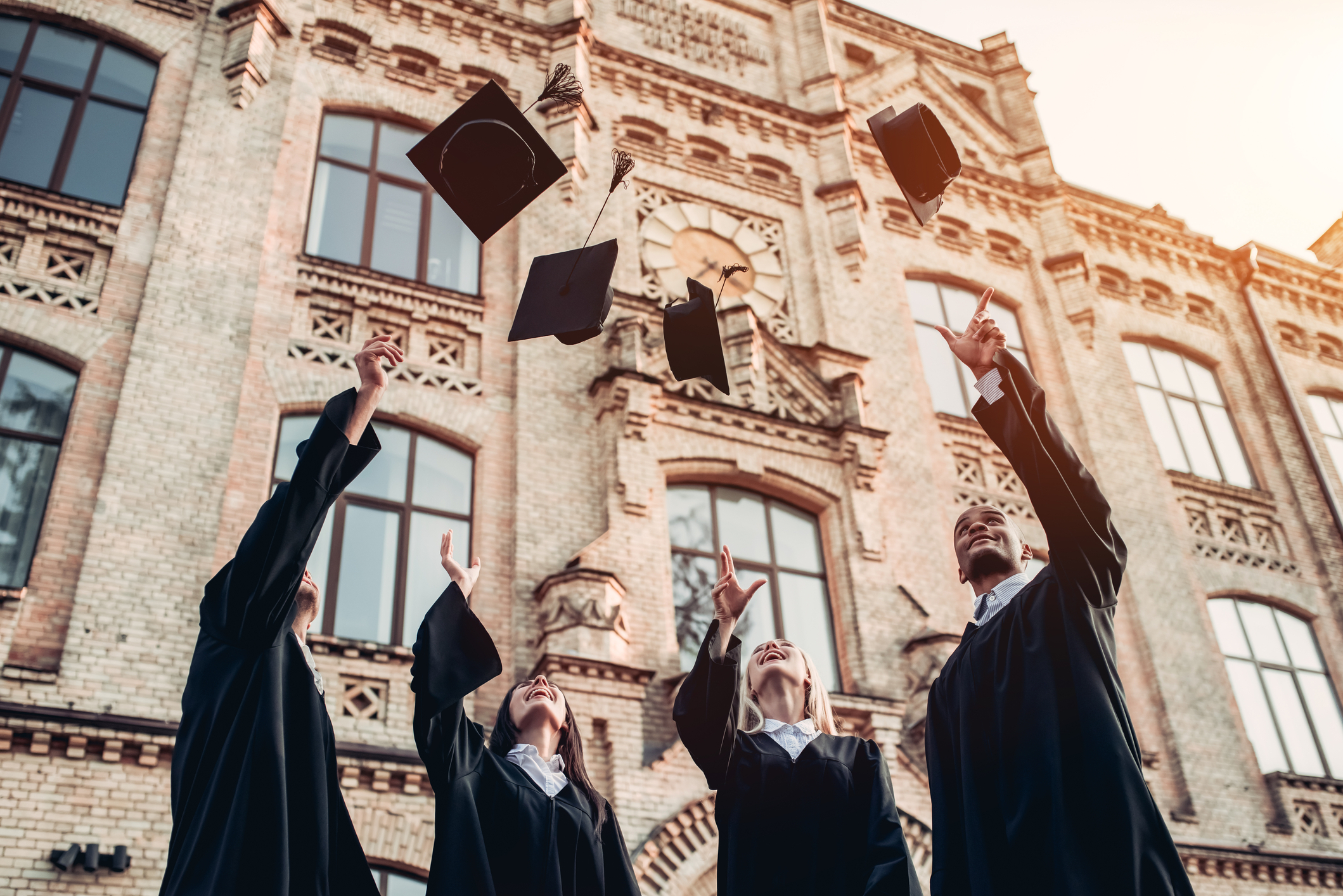 A group of university students throwing mortarboards into the air