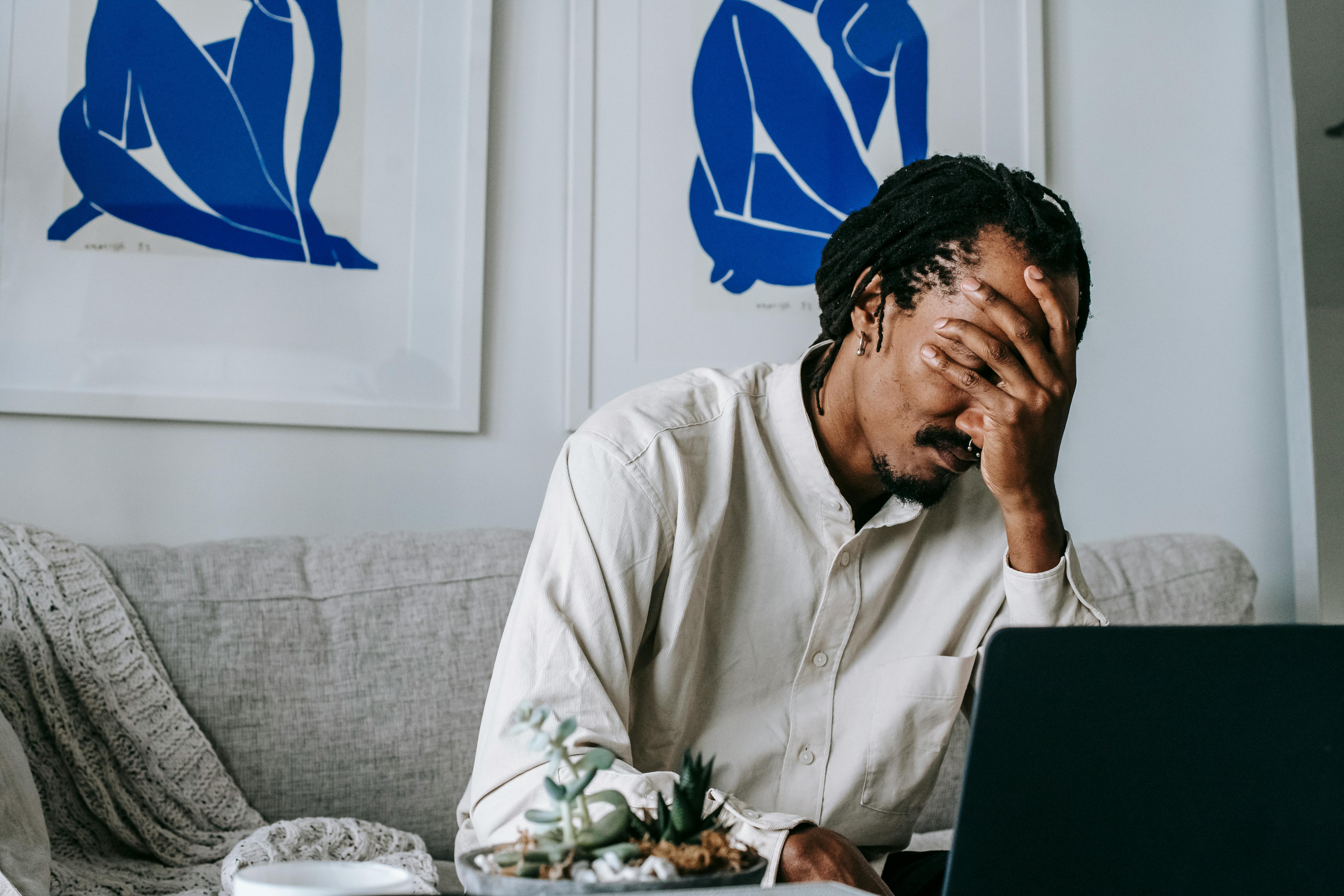 Man in front of laptop with his head in his hands