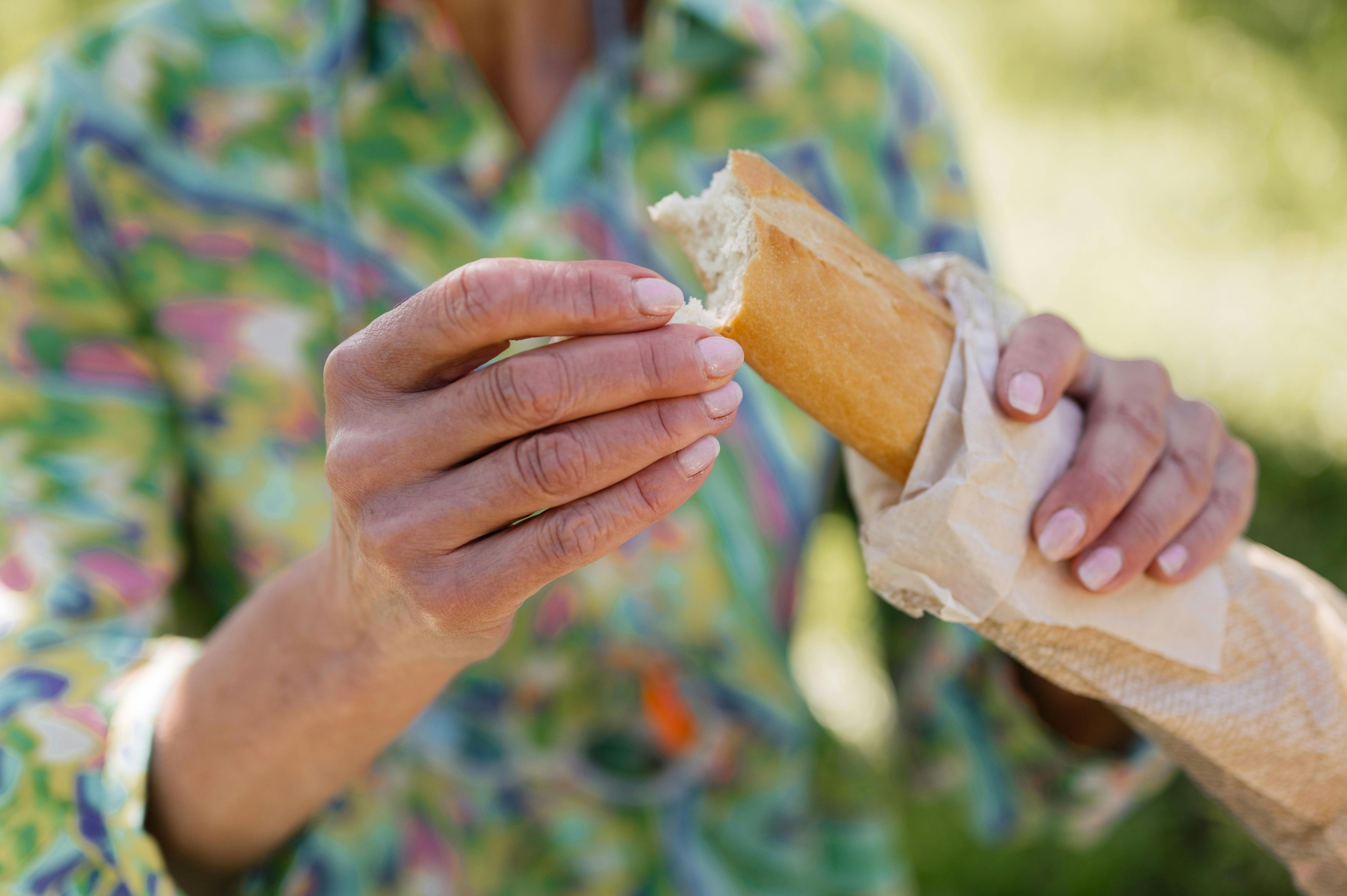 A woman breaking off part of a baguette